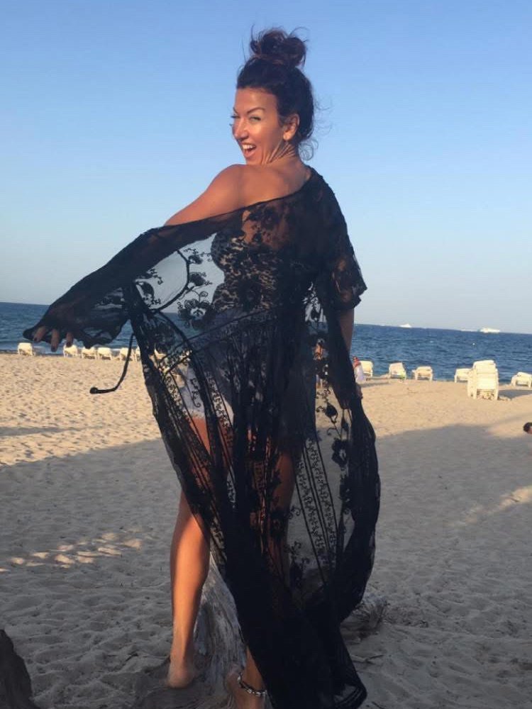 Jessica on an Ibiza beach at dusk, laughing over her shoulder, a black lace kaftan lifting in the breeze