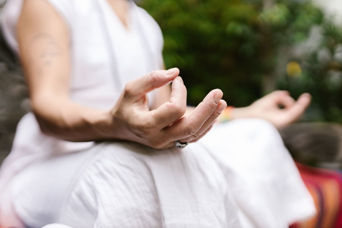 A seated figure in white linen, hand resting on the knee in gyan mudra