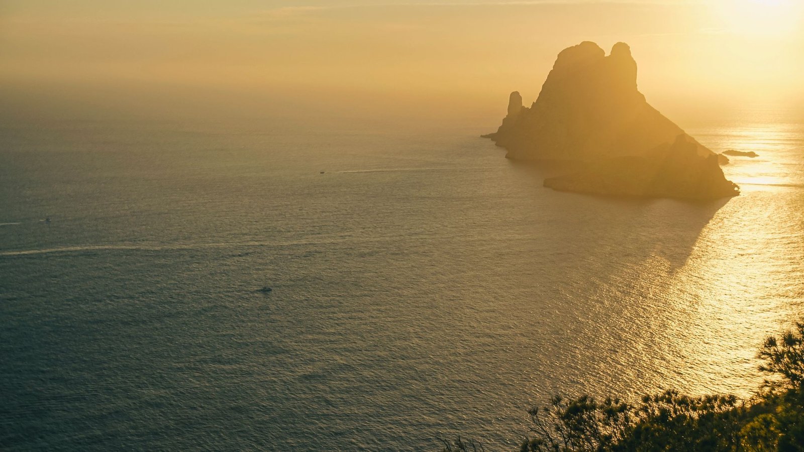 Es Vedrà rising from a sea turned gold by the low sun, seen from the cliffs of Ibiza